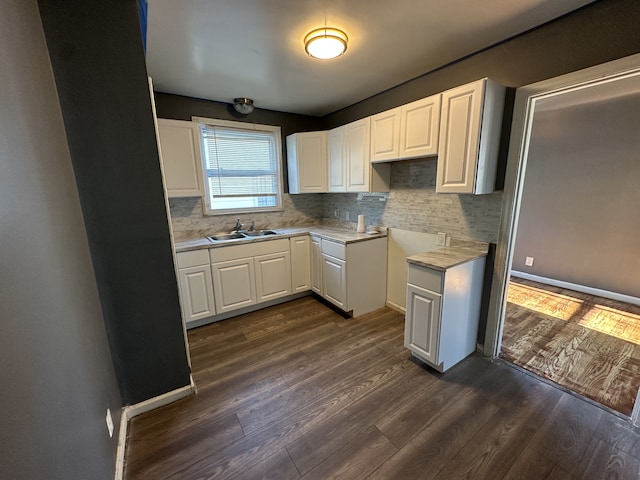 kitchen featuring tasteful backsplash, white cabinetry, dark wood-type flooring, and sink