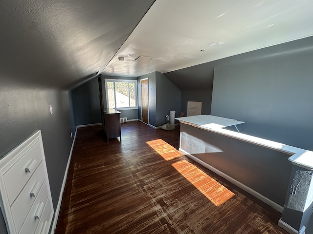 bonus room with a textured ceiling, dark wood-type flooring, and lofted ceiling