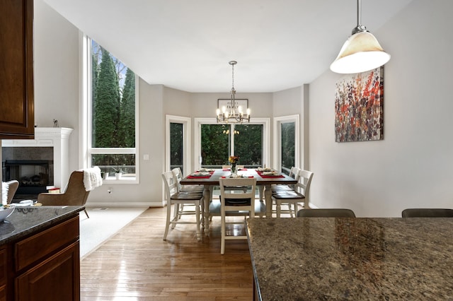 dining room with a fireplace, light hardwood / wood-style flooring, and an inviting chandelier