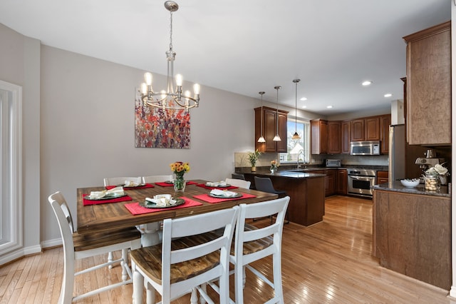 dining area featuring light hardwood / wood-style floors, sink, and a chandelier