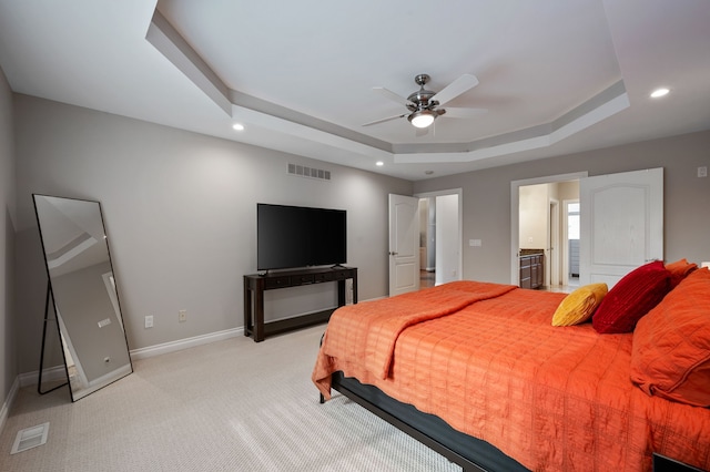 carpeted bedroom featuring connected bathroom, a tray ceiling, and ceiling fan