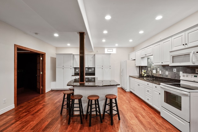 kitchen featuring light hardwood / wood-style floors, a center island, white cabinetry, and white appliances