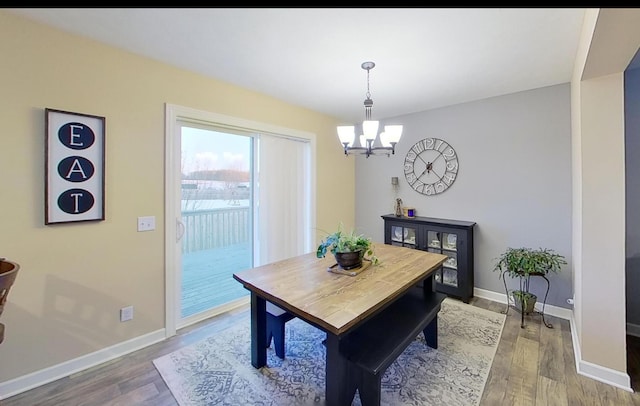 dining space with light wood-style flooring, a notable chandelier, and baseboards
