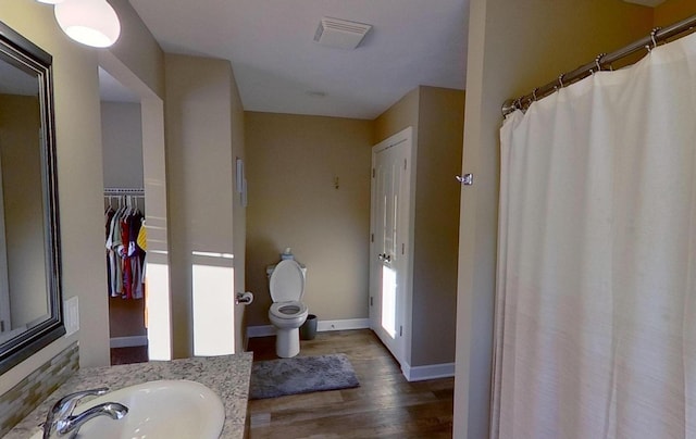 bathroom featuring vanity, baseboards, toilet, visible vents, and wood finished floors