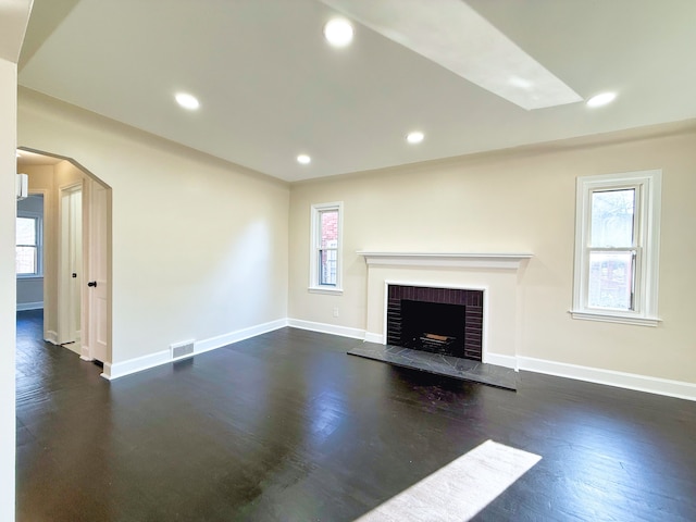 unfurnished living room featuring a fireplace, plenty of natural light, and dark hardwood / wood-style flooring