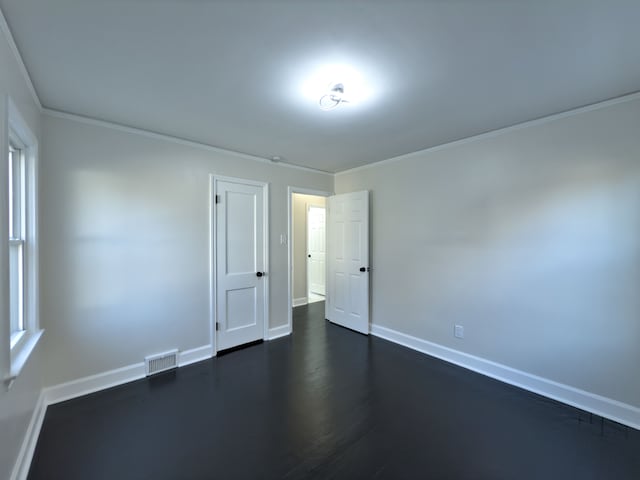 empty room featuring ornamental molding and dark wood-type flooring