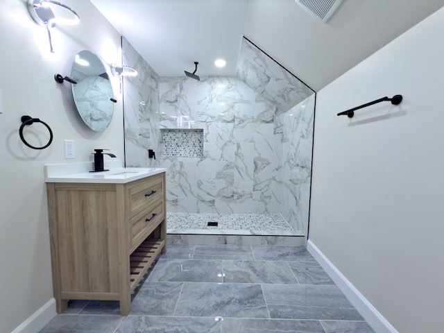 bathroom with a tile shower and vanity