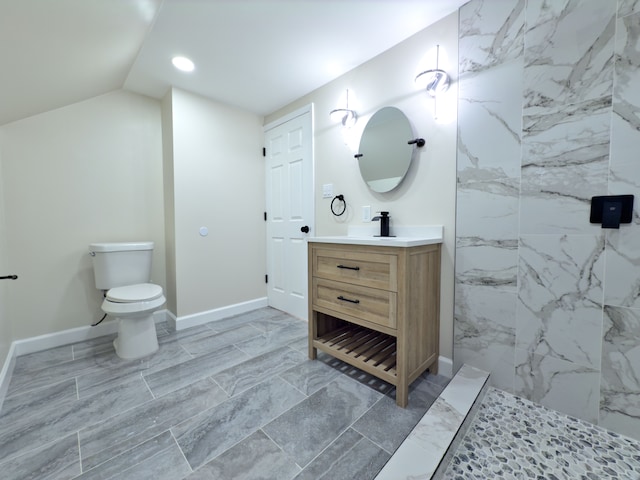 bathroom with vanity, toilet, lofted ceiling, and a tile shower