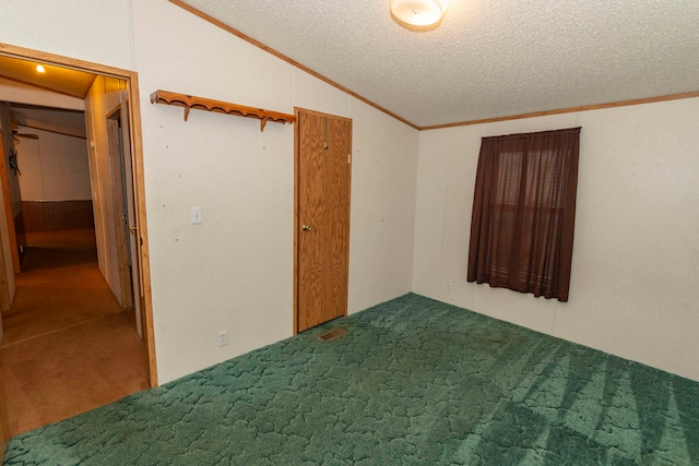 carpeted empty room featuring ornamental molding, a textured ceiling, and vaulted ceiling