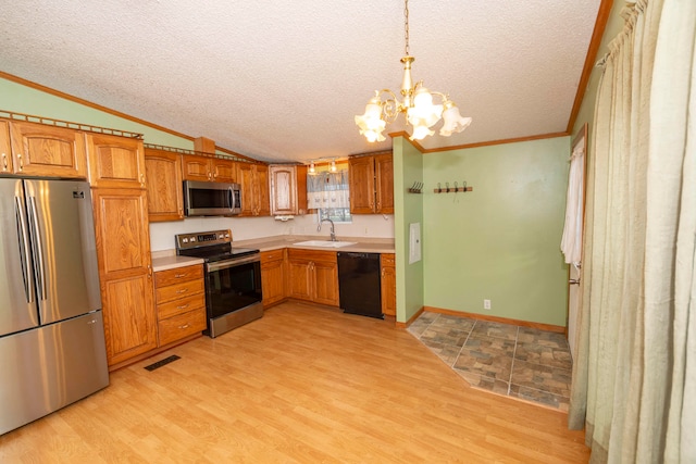 kitchen with pendant lighting, stainless steel appliances, a textured ceiling, and light hardwood / wood-style floors