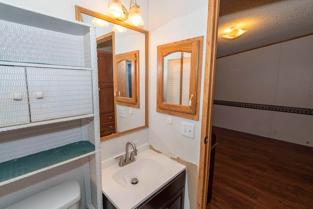 bathroom with hardwood / wood-style floors, vanity, toilet, and a textured ceiling