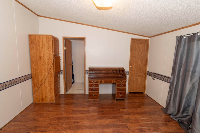 empty room featuring a textured ceiling, crown molding, dark wood-type flooring, and vaulted ceiling