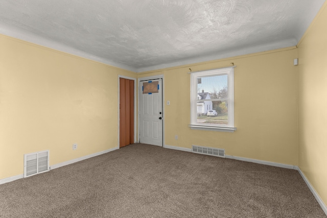 empty room featuring a textured ceiling, carpet floors, and ornamental molding