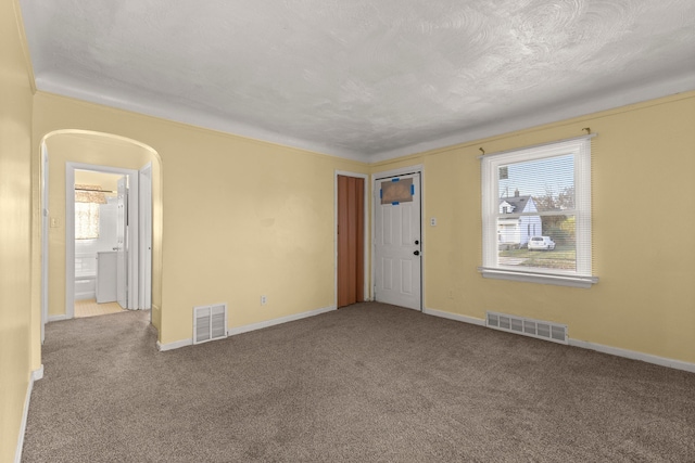 empty room with a textured ceiling and light colored carpet