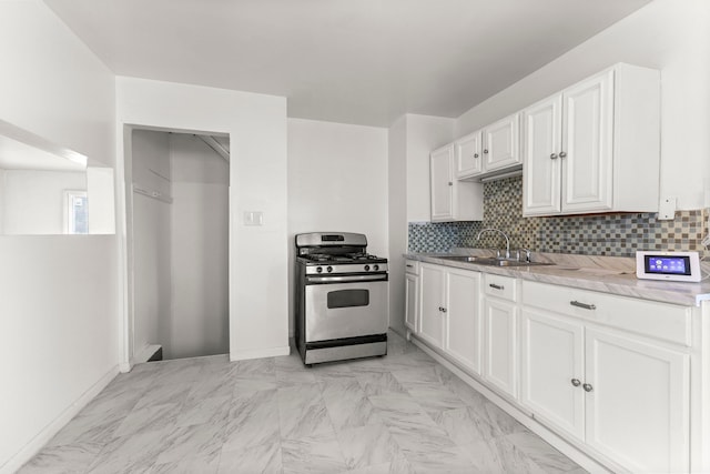 kitchen featuring sink, stainless steel gas range, light stone counters, backsplash, and white cabinets