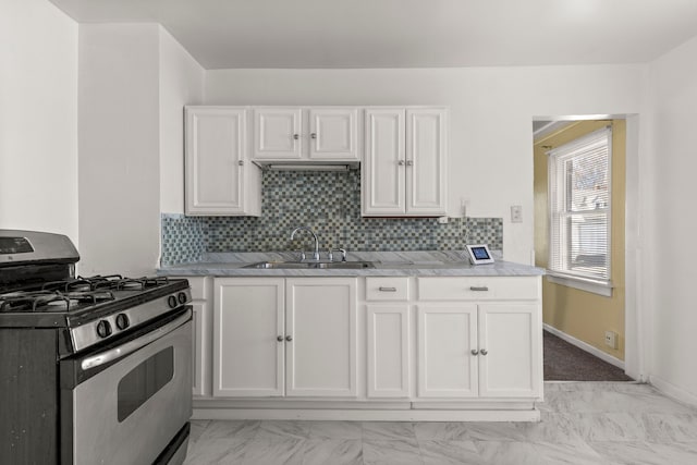 kitchen featuring backsplash, sink, gas range, light stone counters, and white cabinetry