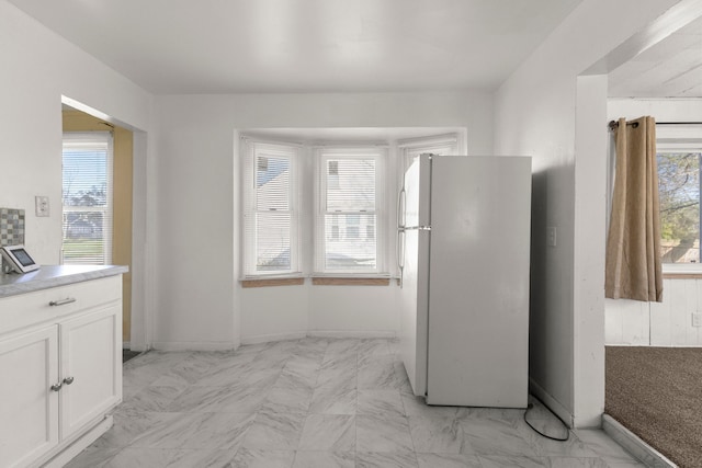 kitchen with white cabinets, plenty of natural light, and white fridge