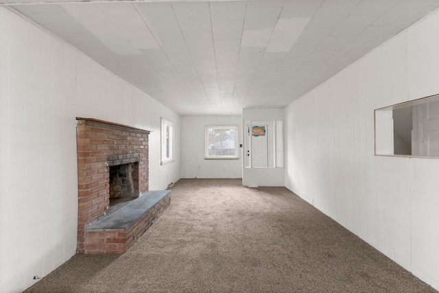 unfurnished living room with wood walls, carpet floors, and a fireplace