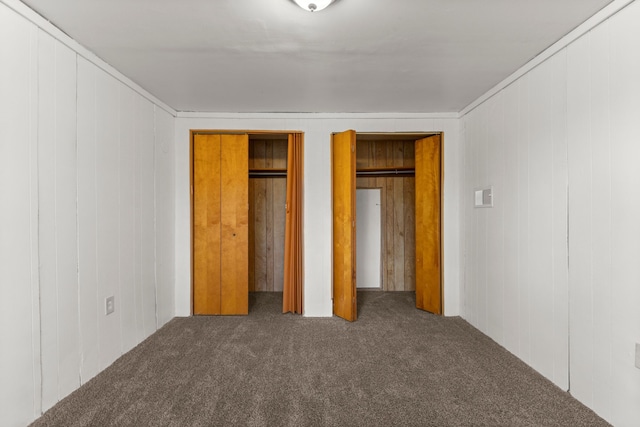 unfurnished bedroom featuring carpet and wood walls