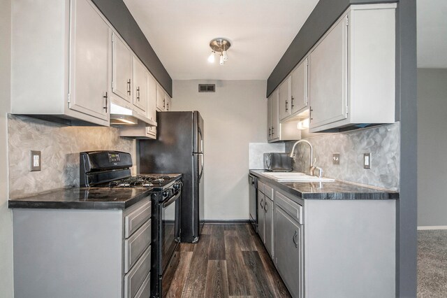 kitchen with dark hardwood / wood-style flooring, sink, white cabinets, and black gas range oven