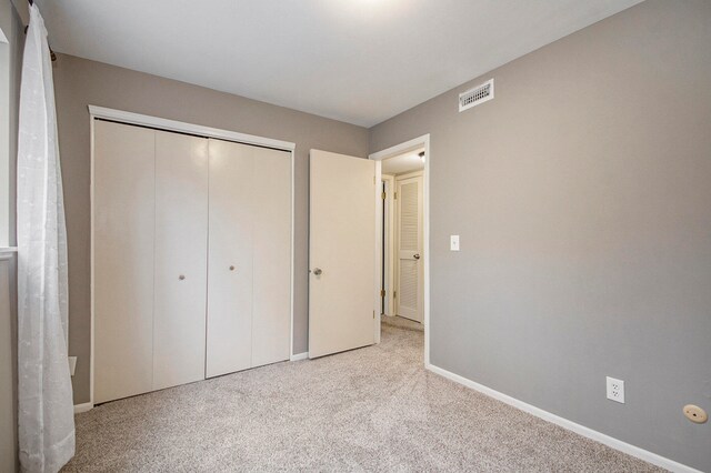 unfurnished bedroom featuring a closet and light colored carpet