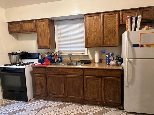 kitchen featuring sink, light tile patterned floors, and white appliances