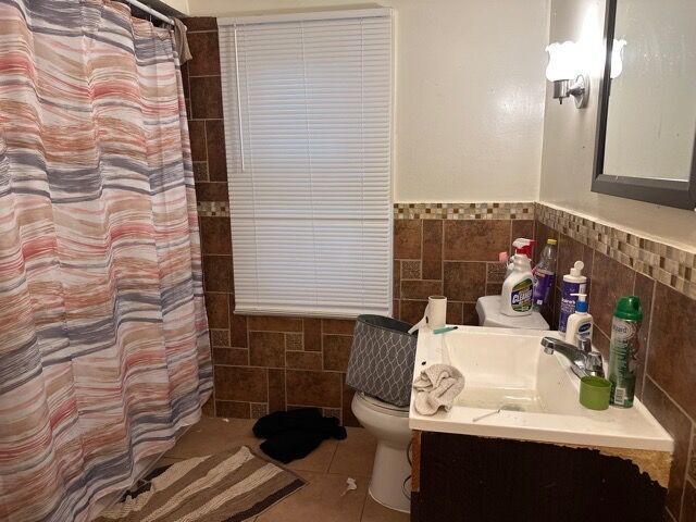 bathroom featuring tile patterned flooring, vanity, tile walls, and toilet