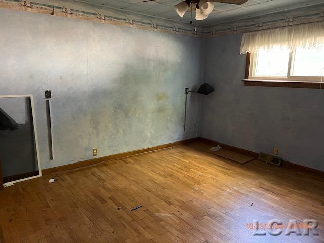 empty room with ceiling fan and hardwood / wood-style flooring