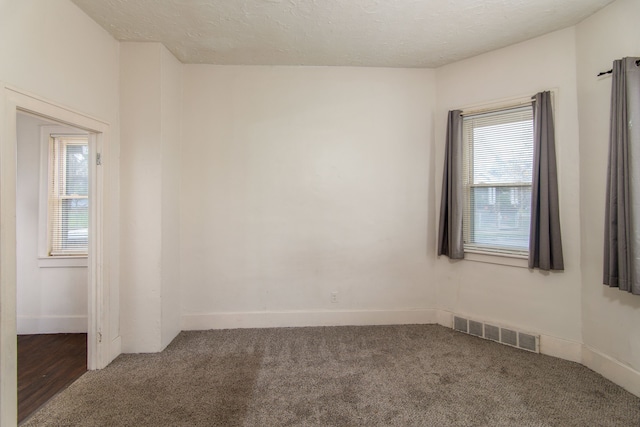 empty room featuring a textured ceiling and dark carpet