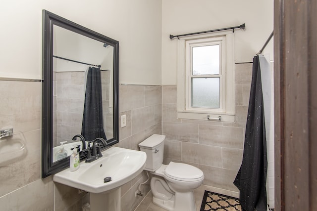 bathroom featuring tile patterned floors, toilet, tile walls, and sink