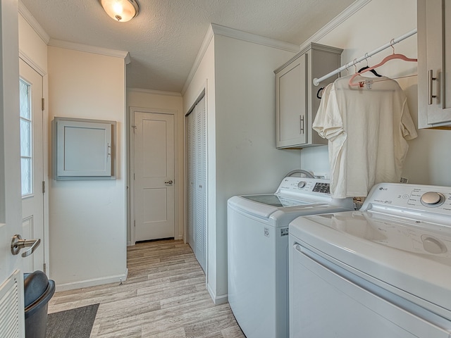 laundry room featuring cabinets, light wood-type flooring, a textured ceiling, crown molding, and independent washer and dryer