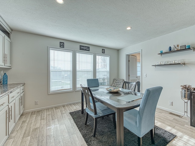 dining space with light hardwood / wood-style floors and a textured ceiling