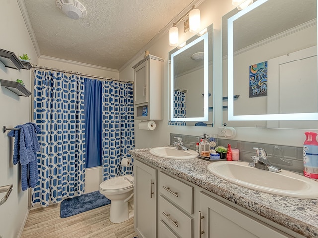 bathroom featuring hardwood / wood-style floors, a textured ceiling, toilet, vanity, and ornamental molding