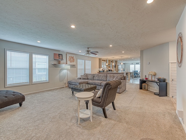 carpeted living room with a textured ceiling and ceiling fan