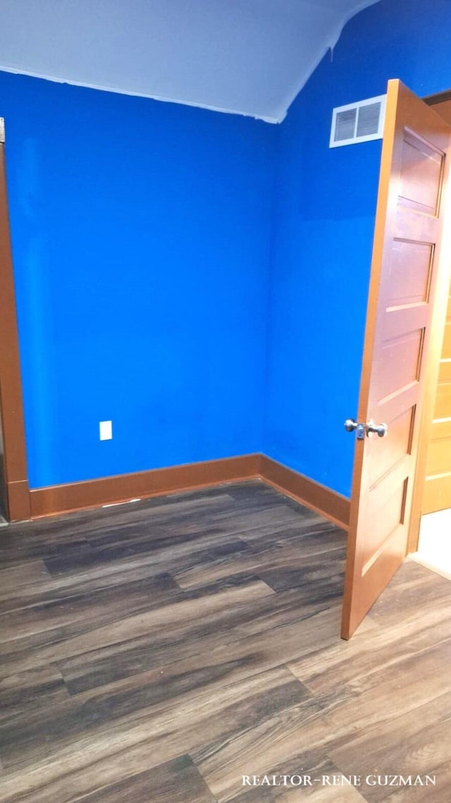 unfurnished room featuring hardwood / wood-style floors and vaulted ceiling