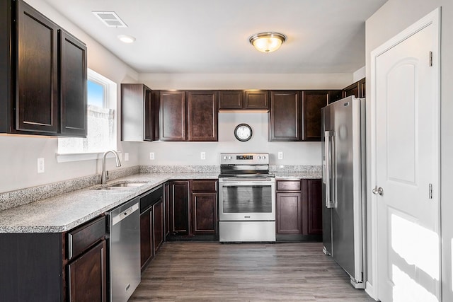 kitchen featuring appliances with stainless steel finishes, sink, dark brown cabinetry, and hardwood / wood-style floors