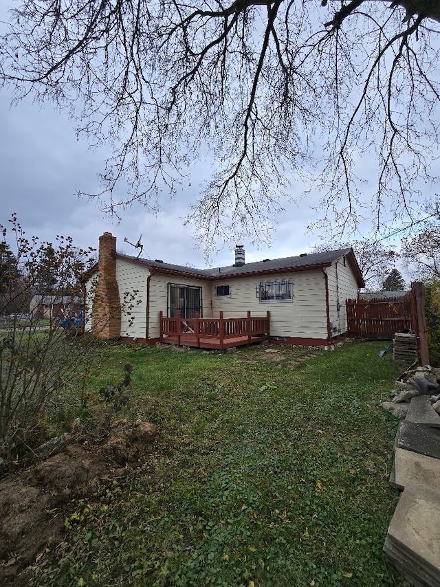 rear view of property featuring a yard and a deck