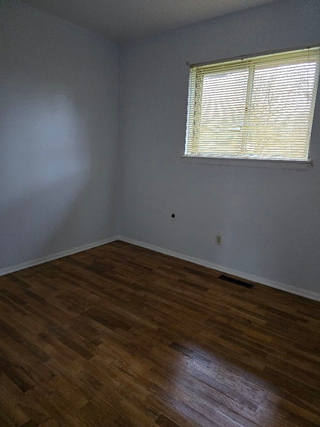 unfurnished room with dark wood-type flooring