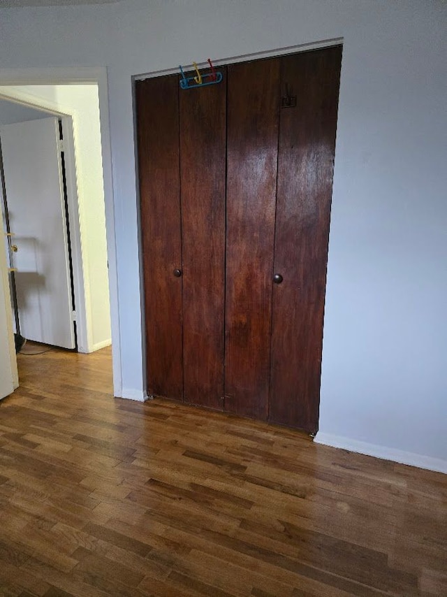 unfurnished bedroom with dark hardwood / wood-style floors and a closet