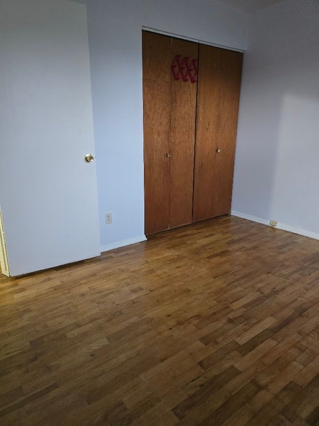 unfurnished bedroom with dark hardwood / wood-style flooring and a closet