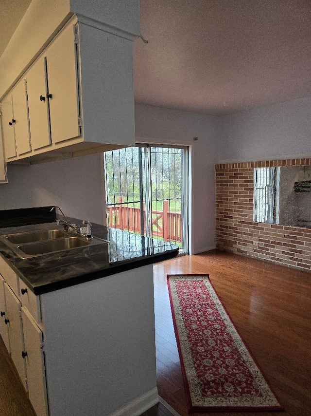 kitchen with a textured ceiling, white cabinetry, sink, and dark wood-type flooring