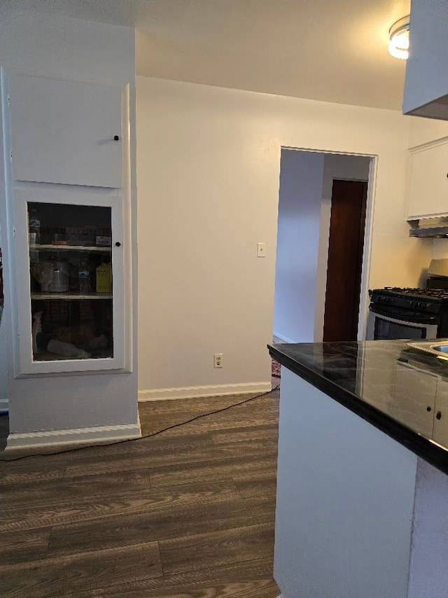 kitchen featuring dark hardwood / wood-style floors, white cabinetry, gas range gas stove, and range hood