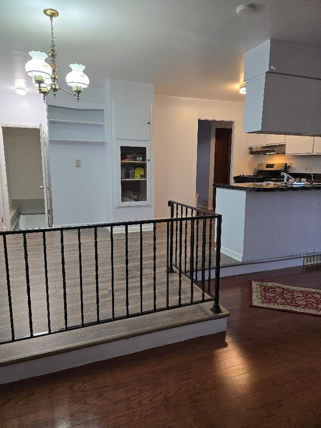 staircase with wood-type flooring and an inviting chandelier