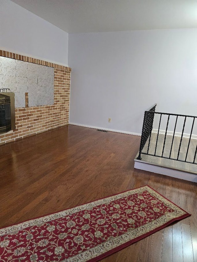 unfurnished living room with wood-type flooring and a wood stove