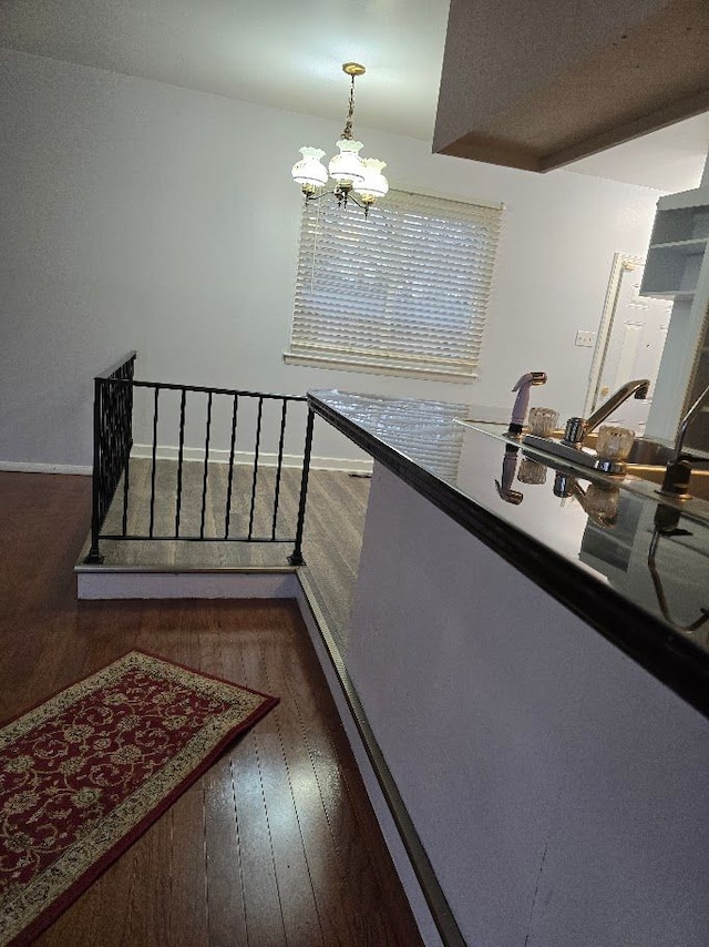 stairway featuring wood-type flooring, sink, and a chandelier