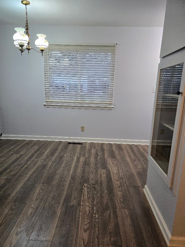 spare room featuring dark hardwood / wood-style floors and an inviting chandelier