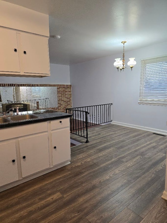 kitchen with sink, decorative light fixtures, dark hardwood / wood-style floors, a notable chandelier, and white cabinetry