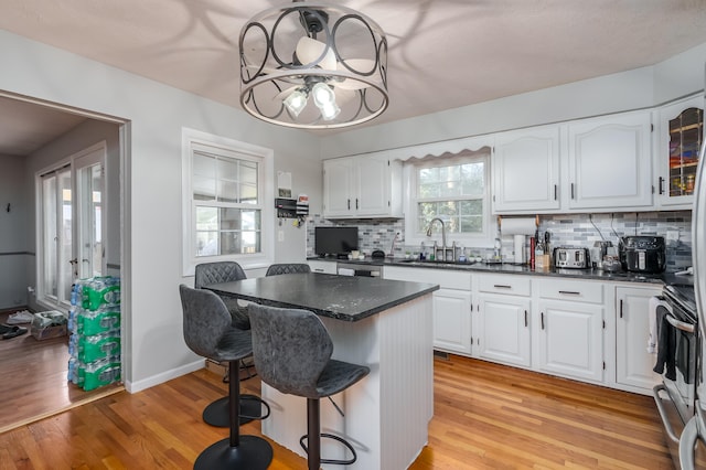 kitchen featuring a breakfast bar, a center island, white cabinetry, and sink