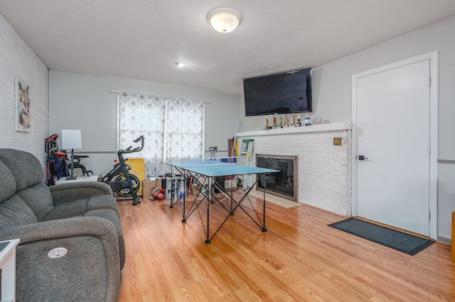 recreation room with hardwood / wood-style floors and a brick fireplace