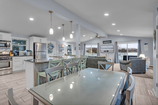 dining area featuring ceiling fan and lofted ceiling with beams